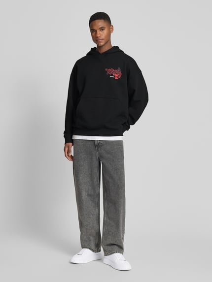 Männermodel trägt Regular Fit Hoodie aus reiner Baumwolle Modell 'DAGETHOOD' von HUGO in Schwarz, Optik: Unifarben, Motiv-Print, Kängurutasche, Sweat, Langarm, Kapuze, Label-Stitching, Ganzkörperansicht von vorne.