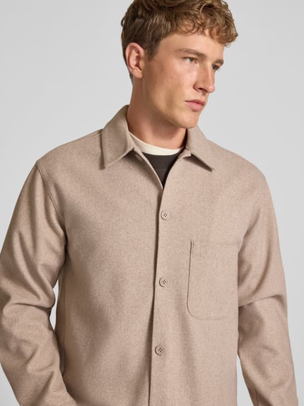 Mężczyzna nosi Regular Fit Hemdjacke mit Kentkragen Modell 'REGENT' od JACK & JONES, beżowy, listwa guzikowa, z przodu kieszeń, krój regular fit, długość tyłu w rozmiarze M: 72 cm, szerokość w rozmiarze M: 50 cm, długość rękawów w rozmiarze M: 64 cm, zdjęcie w półzbliżeniu na górną część ciała.