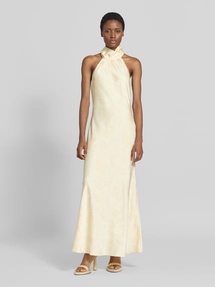 Frauenmodel trägt Abendkleid mit Neckholder Modell 'Fiona' von Neo Noir in Creme mit Satin-Textur, taillierte Passform, Ganzkörperansicht von vorne.