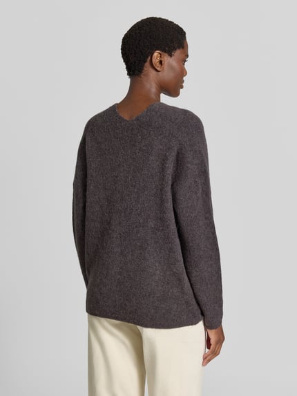 Männermodel trägt sweter z dzianiny z mieszanki wełny z domieszką alpaki, krój regular fit, dekolt w serek, model 'THORA' od MOS MOSH, kolor ciemnoszary, długość tyłu w rozmiarze S: 82 cm, długość rękawów w rozmiarze S: 46 cm, widok całej sylwetki z tyłu.