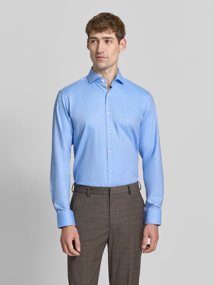Männermodel trägt Regular Fit Businesshemd mit Label-Detail von BOSS in Hellblau, Knopfleiste, Kentkragen, Ganzkörperansicht von vorne.