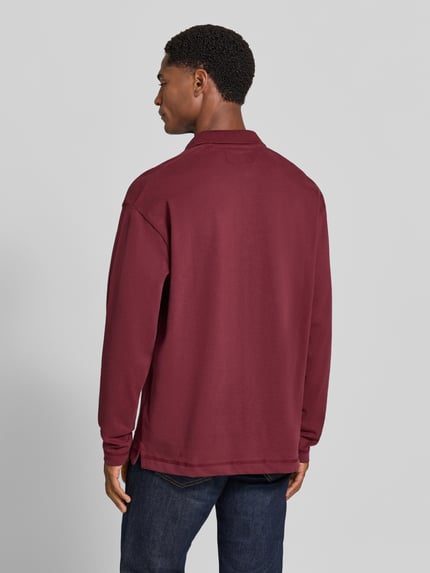 Männermodel trägt Relaxed Fit Poloshirt aus reiner Baumwolle von Marc O'Polo in Dunkelrot, strukturierte Oberfläche, Ganzkörperansicht Rückansicht, Herren Poloshirt.