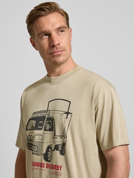 Männermodel trägt T-Shirt mit Motiv-Print Modell 'Baine' von WOODBIRD, beige, reine Bio-Baumwolle, Nahaufnahme Oberkörper.