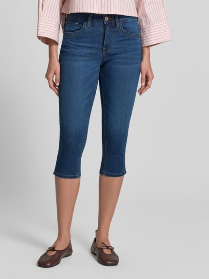 Frauenmodel trägt Slim Fit Caprijeans aus Baumwoll-Mix von Tom Tailor in klassischer Denim-Optik, 5-Pocket-Design, Ganzkörperansicht von vorne.
