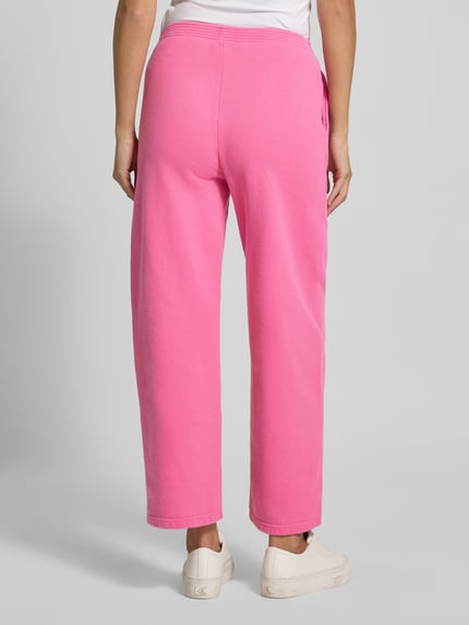Frauenmodel trägt Sweatpants mit Label-Print Modell 'PLIZZY' von American Vintage in Pink, reine Baumwolle, Relaxed Fit, Ganzkörperansicht Rückansicht.