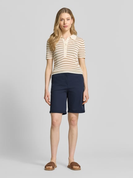 Modelka kobieca nosi Chino-Bermudas mit Gürtel od Christian Berg Woman, granatowa bawełna, krój regular fit, pasek, szerokość w rozmiarze 36: 40 cm, długość nogawki wewnętrznej 23 cm, widok całej sylwetki z przodu.