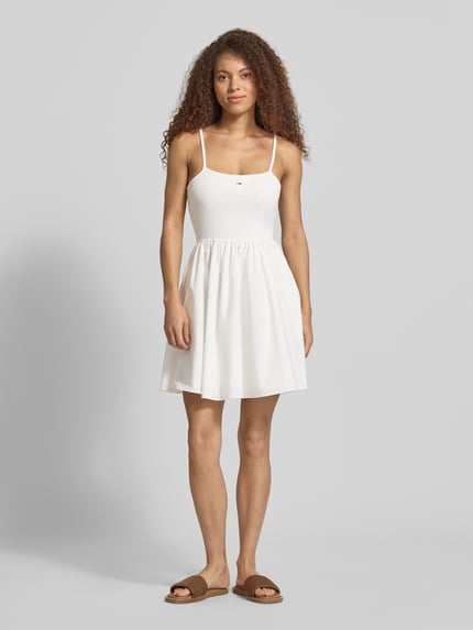 Frauenmodel trägt Tailliertes Freizeitkleid aus reiner Baumwolle von Tommy Jeans, Optik: Unifarben, Mini-Länge, Spaghettiträger, Logo-Stitching, U-Ausschnitt, seitliche Eingrifftaschen, Ganzkörperansicht von vorne.