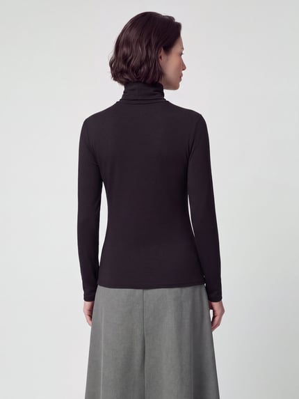Frauenmodel trägt Langarmshirt mit Rollkragen von VERO MODA in Unifarbe, weicher Stoff, glatte Textur, Ganzkörperansicht Rückansicht.