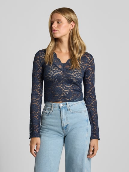 Vrouwenmodel draagt donkerblauw shirt met lange mouwen in mesh-look, Slim Fit Langarmshirt in Spitzen-Mesh-Optik model 'NIKKA' van ONLY, Dames Langarmshirt, bovenlichaam close-up voorkant.