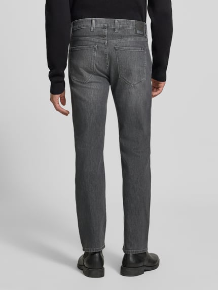 Männermodel trägt graue Relaxed Fit Jeans aus Baumwoll-Mix Modell 'Clint' von Brax, Herren Wide & Loose Fit Jeans, Ganzkörperansicht Rückansicht.