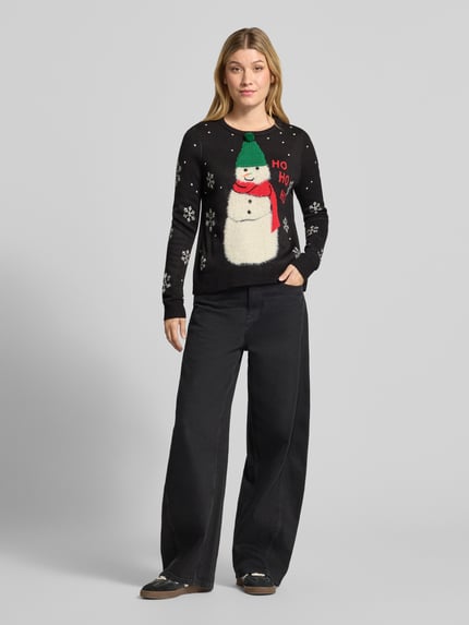 Frauenmodel trägt Pullover mit flauschigem Schneemann-Motiv von VERO MODA, mehrfarbig, Strickoptik, Rundhals, Ganzkörperansicht von vorne.