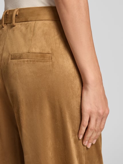 Frauenmodel trägt Cropped Straight Fit Hose mit französischen Eingrifftaschen von Smith and Soul, goldbrauner Material-Mix mit Stretch, Gesäßleistentasche sichtbar, Detailaufnahme, Bundweite 37 cm, Innenbeinlänge 66 cm.