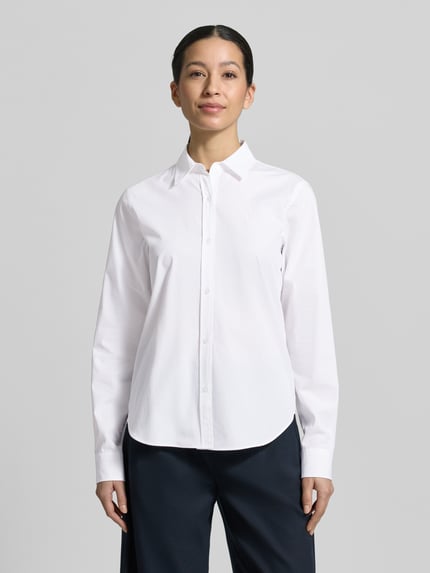 Frauenmodel trägt Regular Fit Hemdbluse aus reiner Baumwolle Modell 'ESSENTIAL' von HUGO, weiß, Popeline, Hemdkragen, unifarben, Logo-Stitching, Ganzkörperansicht von vorne.
