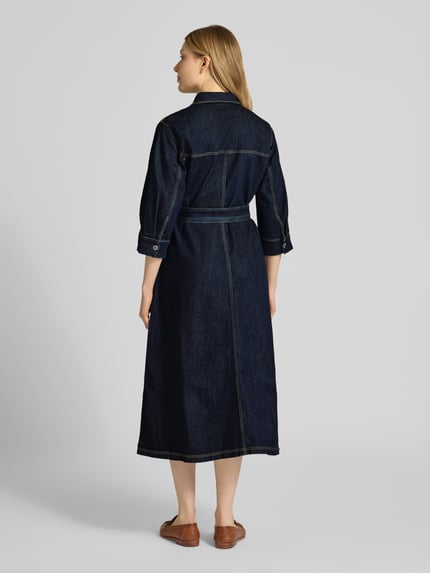 Vrouwenmodel draagt 'Hemdblusenkleid mit Bindegürtel' van Betty Barclay, denimlook in mix van katoen en lyocell, A-lijn, midi-jurk, overhemdkraag, knoopsluiting, strikceintuur, ruglengte maat 36: 121 cm, borstwijdte: 51 cm, mouwlengte: 43 cm, donkerblauw, stevige textuur, zichtbare stiksels. Ganzkörperaanzicht achteraan.