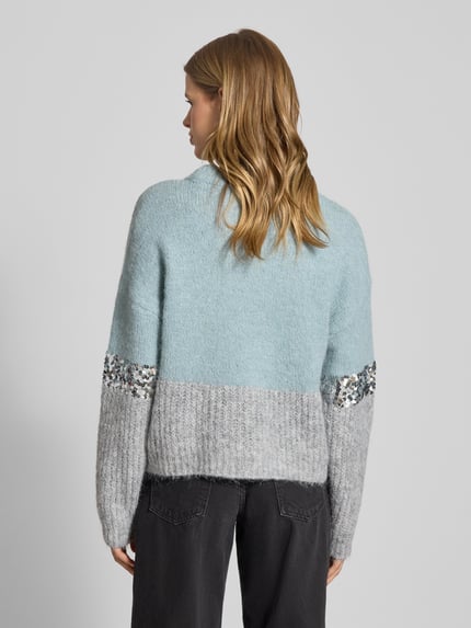 Frauenmodel trägt Relaxed Fit Strickpullover mit Woll-Anteil Modell 'MAINE' von Only in Two-Tone-Optik mit Paillettenbesatz, Ganzkörperansicht Rückansicht.