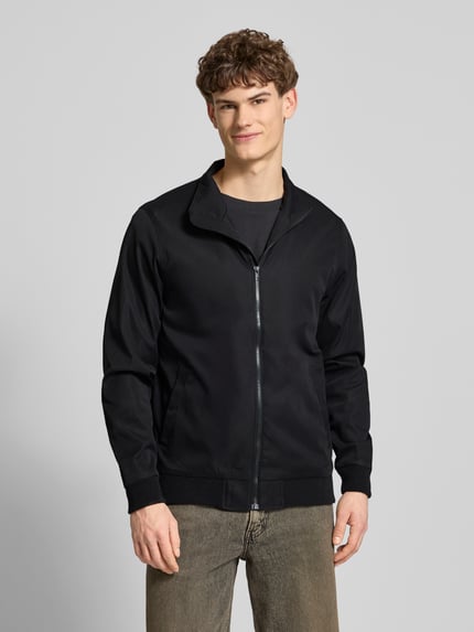 Männermodel trägt Regular Fit Jacke mit Stehkragen Modell 'Hefi' von Blend in Schwarz, Baumwolle, Reißverschluss, Eingrifftaschen, Ganzkörperansicht von vorne.