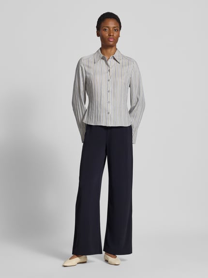 Frauenmodel trägt Relaxed Fit Stoffhose mit Tunnelzug von MM by Max Mara, dunkel und weit geschnitten, seitliche Eingrifftaschen, Ganzkörperansicht von vorne.
