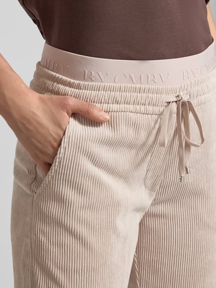 Kobiece modelka nosi Cordhose mit elastischem Bund Modell 'EDEN' von Cambio, jasny beż, prążkowana faktura, materiał mix stretch, zbliżenie pasa.