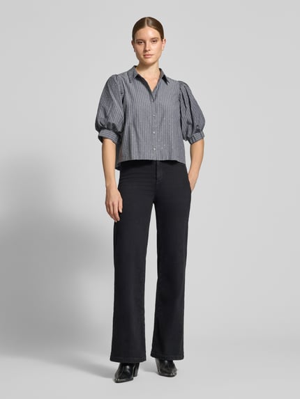 Frauenmodel trägt Bluse mit Puffärmeln Modell 'Etta' von Neo Noir, Boxy Fit, Kentkragen, Knopfleiste, Ganzkörperansicht von vorne.