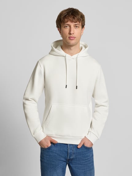 Männermodel trägt Hoodie mit Kapuze Modell 'BRADLEY' von Jack & Jones in weiß, lockerer fit, kangoeroezak, materiaal-mix, ganzkörperansicht von vorne.