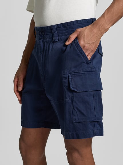 Männermodel trägt Relaxed Fit Cargoshorts aus reiner Baumwolle von Polo Ralph Lauren, look: effen, webstructuur, gestikt logo, steekzakken, achterzakken met knoop, cargozakken, knoop- en ritssluiting, met riemlussen, puur katoen. Detailaufnahme.