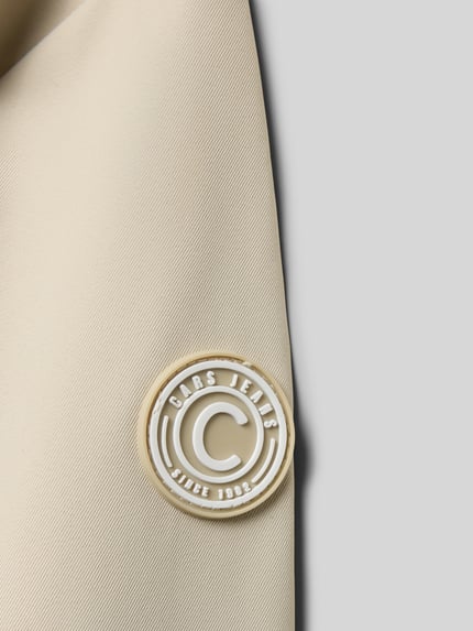 Detailopname, crèmekleurige stof met witte logo-applicatie Regular fit Jacke mit Logo-Applikation Modell 'Zinnia' van CARS JEANS, afneembare capuchon, steekzakken, opstaande kraag, ruglengte maat 140: 58 cm, schouderbreedte 36 cm, mouwlengte 55 cm