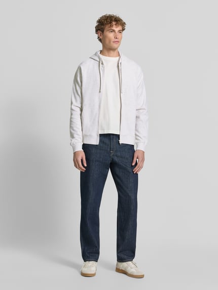 Männermodel trägt Relaxed Fit Sweatjacke aus reiner Baumwolle von s.Oliver RED LABEL, helle Farben, dezente Struktur, Ganzkörperansicht von vorne.