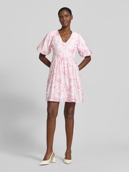 Frauenmodel trägt Tailliertes Freizeitkleid aus Viskose-Mix Modell 'BLISS' von Vero Moda, Optik: Allover-Muster, Mini-Länge, V-Ausschnitt, Ballonärmel, feine Webstruktur, Ganzkörperansicht von vorne.