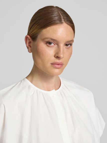 Vrouwenmodel draagt Regular Fit Bluse aus reiner Baumwolle van Weekend Max Mara, look: effen, maokraag, ronde hals, knoopsluiting, korte mouw met split, materiaal: puur katoen. Nahaufnahme bovenlichaam.