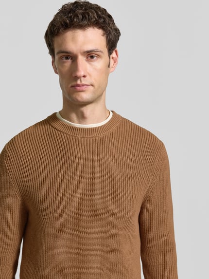 Männermodel trägt Regular Fit Strickpullover aus reiner Baumwolle von MCNEAL in Braun mit Rundhalsausschnitt, Nahaufnahme Oberkörper.