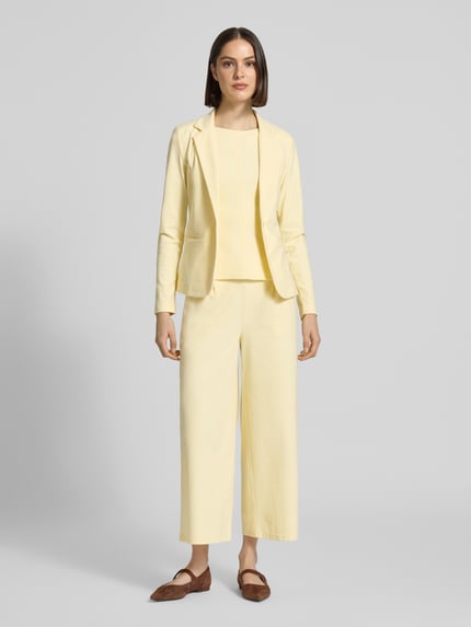 Frauenmodel trägt Slim Fit Blazer mit Paspeltaschen Modell 'KATE' von ICHI in Hellgelb, Baumwoll-Mix mit Stretch, Ganzkörperansicht von vorne.