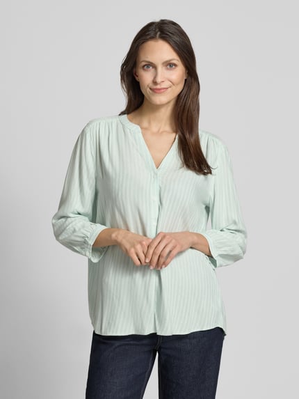 Frauenmodel trägt Comfort Fit Langarmbluse aus reiner Viskose von Tom Tailor mit Allover-Muster, Mao-Kragen und 3/4-Arm, Nahaufnahme Oberkörper.