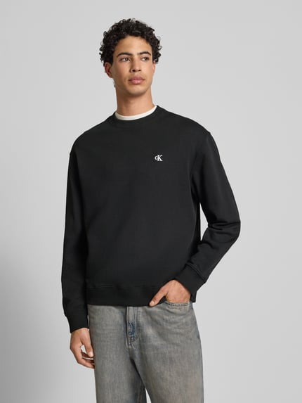 Mannelijk model draagt zwart Sweatshirt met Label-Stitching van Calvin Klein Jeans, ronde hals, ribboorden, katoen, vooraanzicht, bovenlichaam.