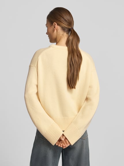 Frauenmodel trägt Strickpullover aus Woll-Mix Modell 'GRISUC' von MANGO in Beige, strukturierte Oberfläche, Relaxed Fit, Ganzkörperansicht Rückansicht.