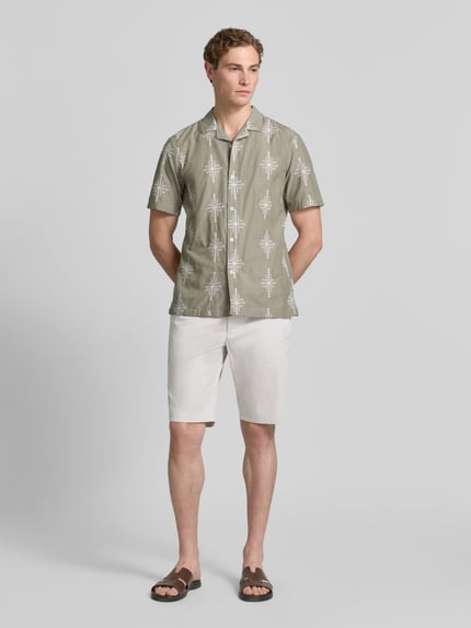 Männermodel trägt Bermudas aus Light Baumwolle mit Gürtel von Christian Berg Men in Weiß, Regular-Fit, mit Eingrifftaschen und Gesäßtaschen, Bundweite bei Größe 50: 47 cm, Innenbeinlänge 28 cm, Ganzkörperansicht von vorne.