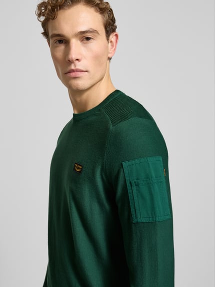 Männermodel trägt grünen Strickpullover mit Label-Detail von PME Legend aus reiner Baumwolle, Rundhalsausschnitt, Nahaufnahme Oberkörper.