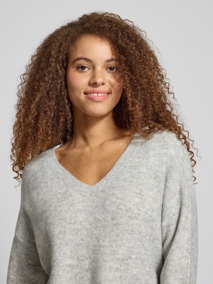 Frauenmodel trägt Regular Fit Strickpullover mit Paillettenbesatz Modell 'ARIZONA' von Only in Melange-Optik, Nahaufnahme Oberkörper.