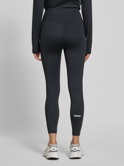Vrouwenmodel draagt Legging met logo en elastische band van EA7 Armani, materiaalmix met stretch, nauwsluitende pasvorm, logodetail, ganzkörperansicht rückansicht.