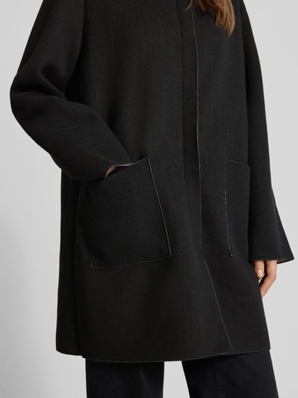 Frauenmodel trägt Mantel mit Kapuze und Eingrifftaschen von Apricot, Material-Mix, verdeckter Verschluss, Nahaufnahme Oberkörper.