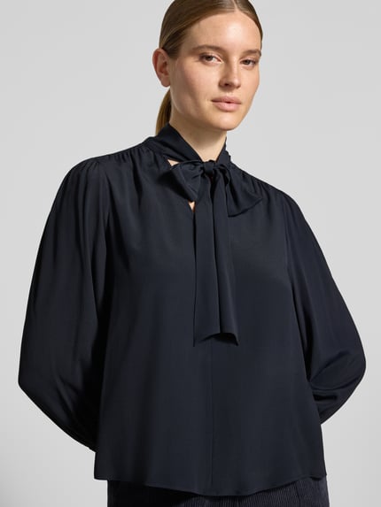 Modelka nosi Relaxed Fit Bluse mit Seiden-Anteil von Luisa Cerano, Mieszanka acetatu z jedwabiem, ozdobna kokarda, elastyczne zakończenia rękawów, rękaw o dł. 3/4, długość tyłu w rozmiarze 36: 62 cm, długość rękawów: 50 cm, widok na górną część ciała z przodu.