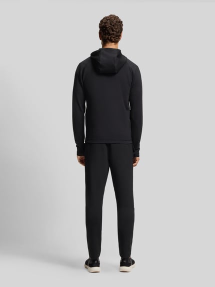 Männermodel trägt schwarze Regular Fit Trainingsjacke aus schnell trocknendem Gewebe Modell 'SICON ACTIVE' von BOSS Green, Ganzkörperansicht Rückansicht.