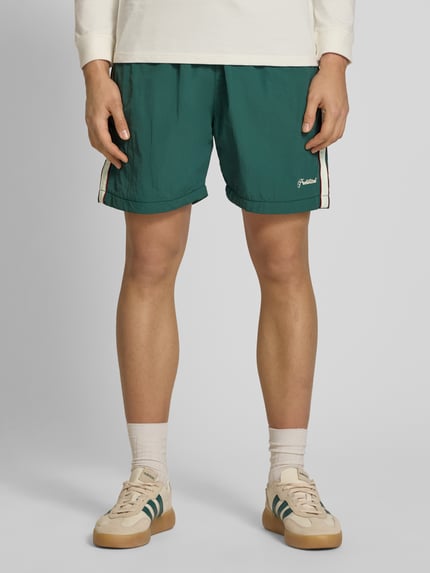 Männermodel trägt grüne Shorts mit Label-Stitching Modell 'Slipstream' von PROHIBITED, Regular Fit, elastischer Bund, Ganzkörperansicht von vorne.
