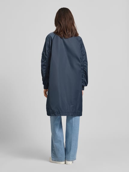 Modelka nosi Regular Fit kurtka ze stójką model 'Ali' od Beaumont Amsterdam, gładki granatowy materiał, marszczenia, wpuszczane kieszenie, zamek błyskawiczny dwustronny, elastyczne zakończenia rękawów, długość tyłu w rozmiarze 36: 97 cm, szerokość ramion w rozmiarze 36: 47 cm, szerokość klatki piersiowej w rozmiarze 36: 55 cm, długość rękawów w rozmiarze 36: 60 cm, widok całopostaciowy z tyłu.