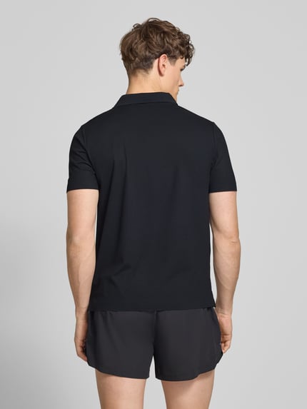 Männermodel trägt schwarzes Slim Fit Poloshirt mit Logo Modell 'EDMOND' von Ellesse, Material-Mix mit Stretch-Anteil, Rückenlänge 63 cm, Ganzkörperansicht Rückansicht.