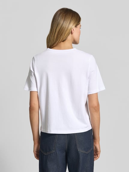 Frauenmodel trägt Regular Fit T-Shirt aus reiner Baumwolle Modell 'ASSIA' von Selected Femme in Weiß, unifarben, Ziernähte, Ganzkörperansicht Rückansicht.