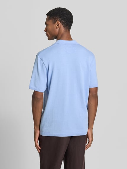Männermodel trägt Relaxed Fit Poloshirt aus reiner Baumwolle von Armedangels, Optik: Unifarben, Feinstrick, Ganzkörperansicht Rückansicht.