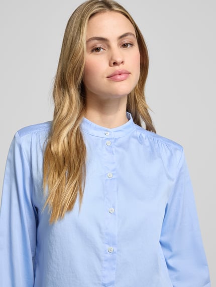 Frauenmodel trägt Regular Fit Hemdbluse aus reiner Baumwolle von Marc O'Polo in Hellblau, Stehkragen, Knopfleiste, Nahaufnahme Oberkörper.