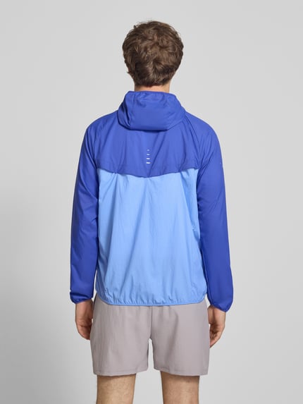 Männermodel trägt Trainingsjacke mit Logo-Print und Kapuze von NIKE TRAINING in Blau, Reißverschluss, glatte Struktur, Ganzkörperansicht Rückansicht.
