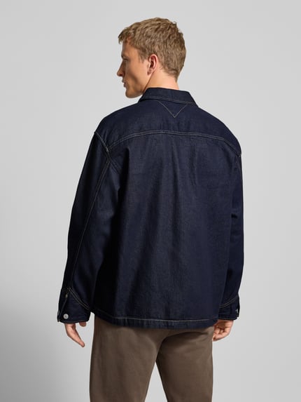 Männermodel draagt Regular Fit Jeansjacke aus reiner Baumwolle van Tommy Jeans in donkere melangelook, denim, knoopsluiting, zij- en borstzakken, lange mouwen, puur katoen. Ganzkörperansicht Rückansicht.