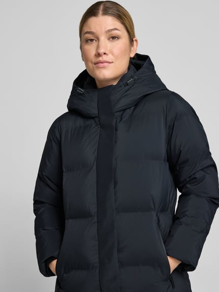 Frauenmodel trägt Steppmantel mit Reißverschlusstaschen Modell 'MAYLA4' von khujo in Dunkelblau, Regular Fit, Nahaufnahme Oberkörper.